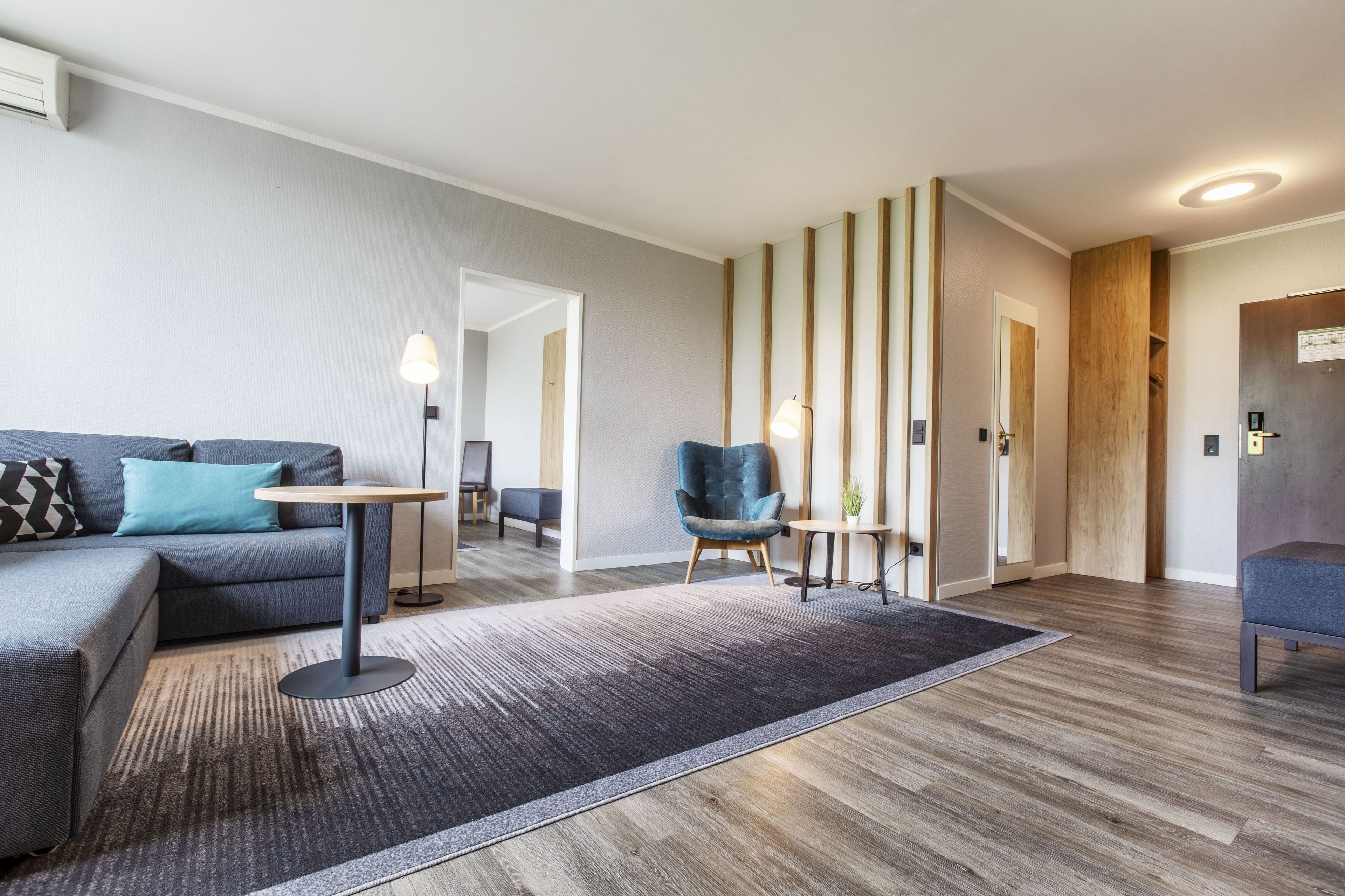 Ein modernes Wohnzimmer mit einer Couch, einem Sessel, einem kleinen Tisch und einem Teppich.