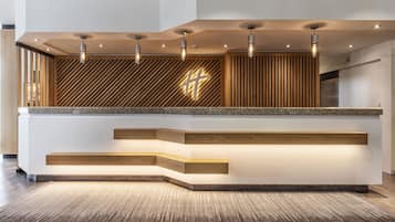 Una recepción con diseño moderno, que incluye una pared de listones de madera y una cruz iluminada destacada.