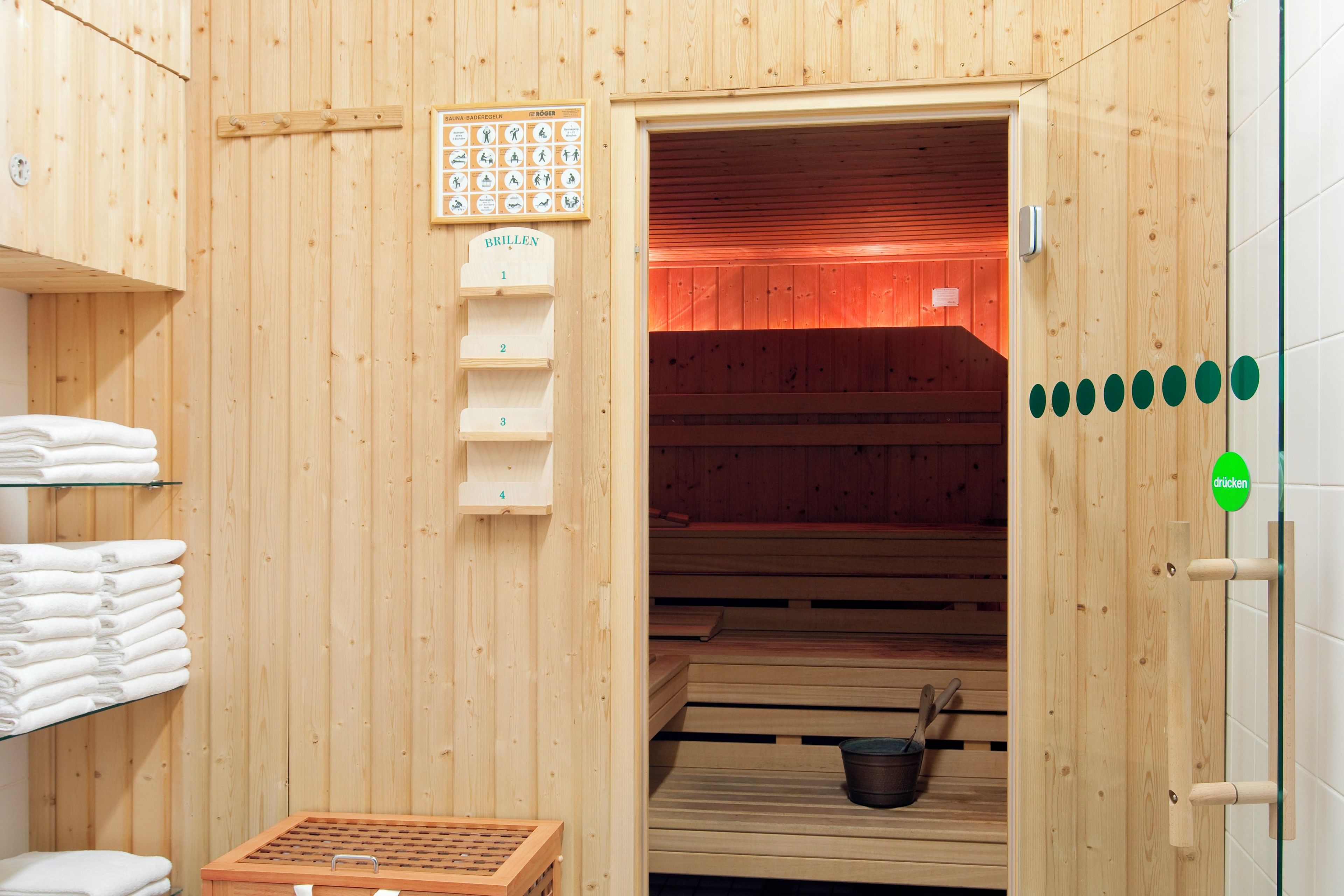 A sauna room with wooden walls, a wooden bench, a towel rack, and a sauna sign.
