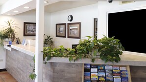 A reception desk with framed pictures, a clock, and a plant. - The Stevenson Monterey (Monterey)