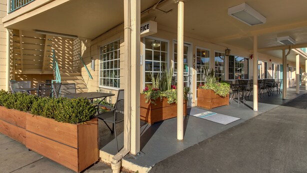 A covered outdoor seating area with wooden planters, tables, and chairs. - The Stevenson Monterey (Monterey)