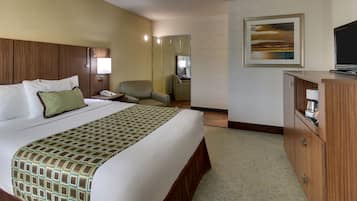 Hotelkamer met een groot bed, een bureau met stoel, een kledingkast, een schilderij aan de muur en een televisie.