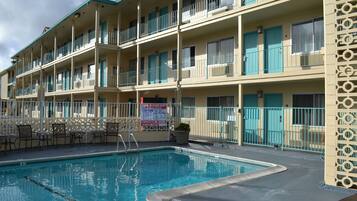 A multi-story hotel with a swimming pool, outdoor seating, and balconies.