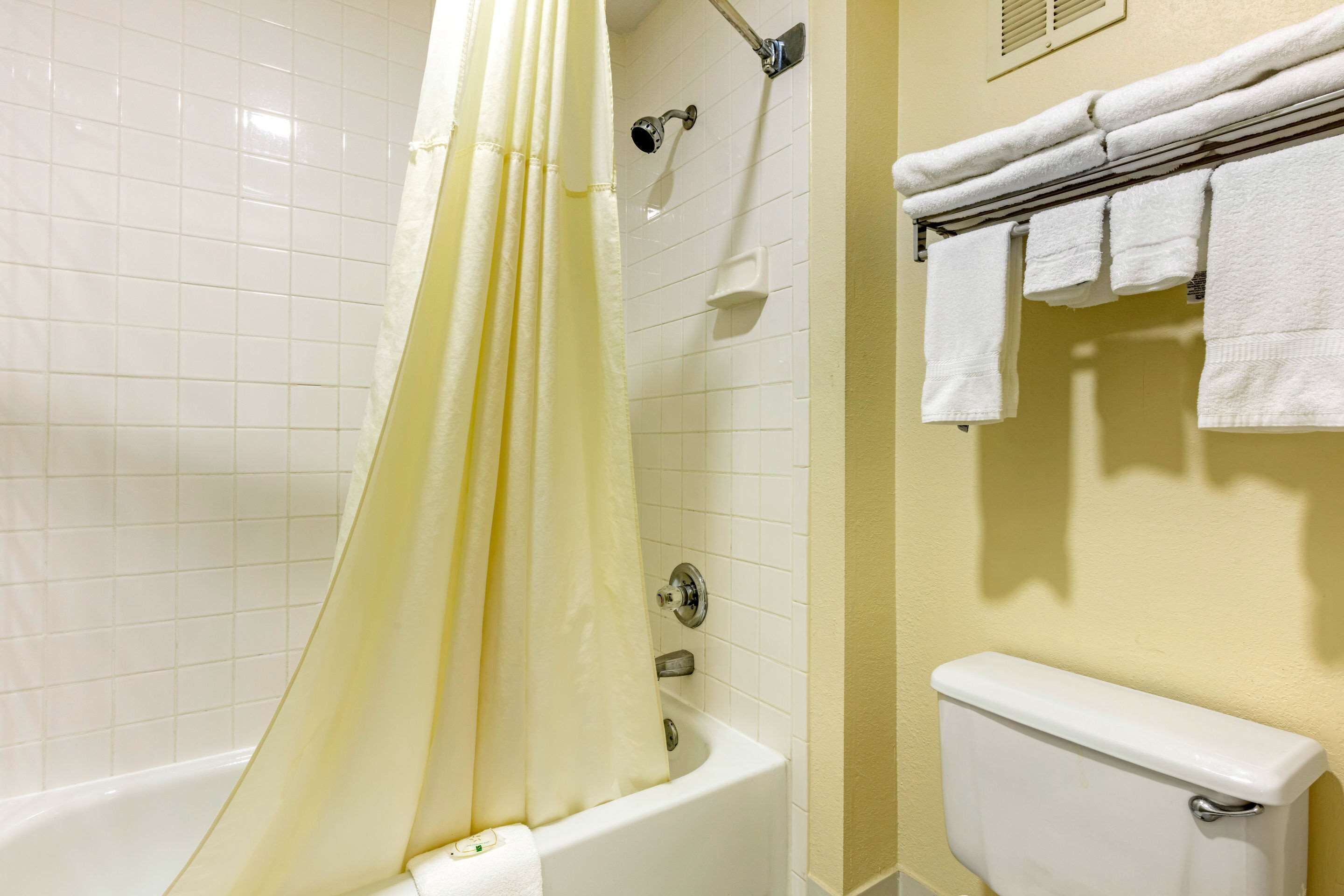 A bathroom with a bathtub, a toilet, and a towel rack with towels.