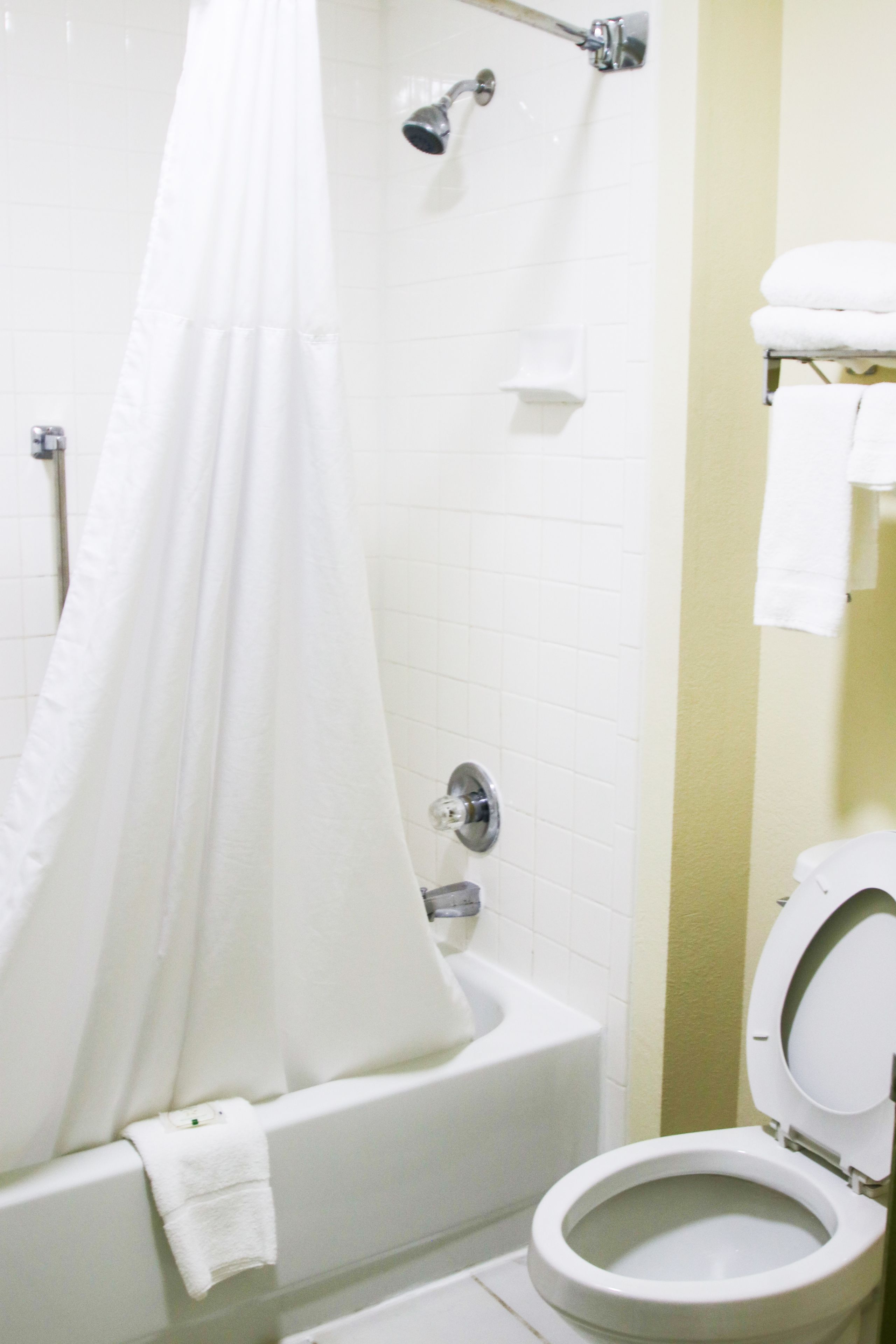 A bathroom with a bathtub, a showerhead, and a toilet.