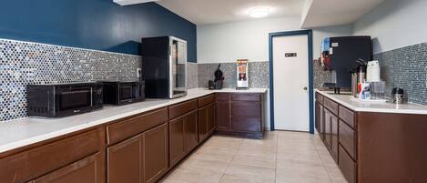 A narrow kitchen with dark brown cabinets, a white countertop, and a tiled backsplash.