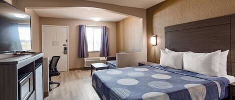 Una habitación de hotel con cama, escritorio, silla y televisor.