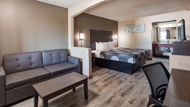 Una habitación de hotel moderna con sofá, cama, una mesita y un escritorio con silla.