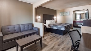 A modern hotel room with a sofa, a bed, a small table, and a desk with a chair. - SureStay Hotel by Best Western Olathe (Olathe)