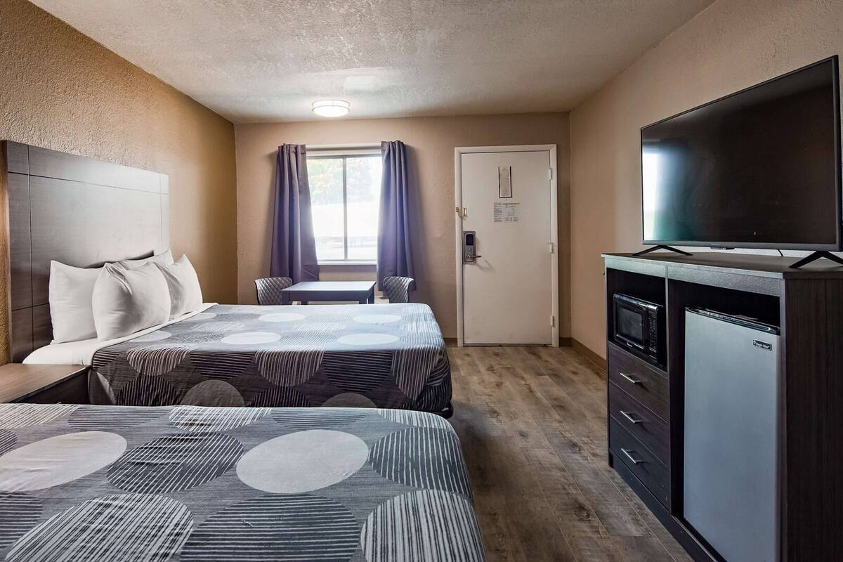 Una habitación de hotel con dos camas, un escritorio, televisor y minibar.