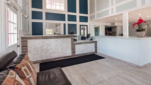 Un área de recepción moderna con mostrador, zona de estar y vistas a la cocina.
