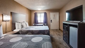 Habitación de hotel con dos camas, televisión, minibar y ventana con cortinas.