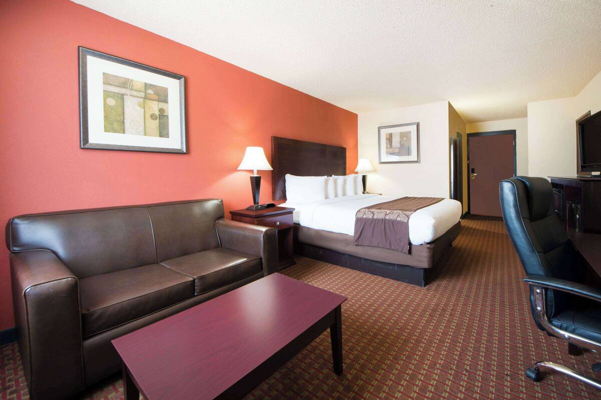 A hotel room with a bed, a sofa, a desk, and a TV.