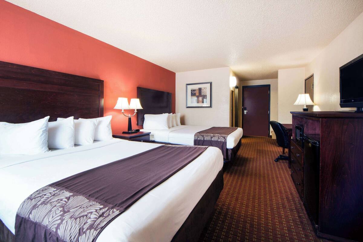 A hotel room with two beds, a desk, a television, and a wardrobe.
