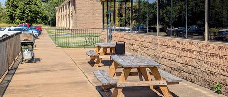 An outdoor patio area with picnic tables and a brick wall.