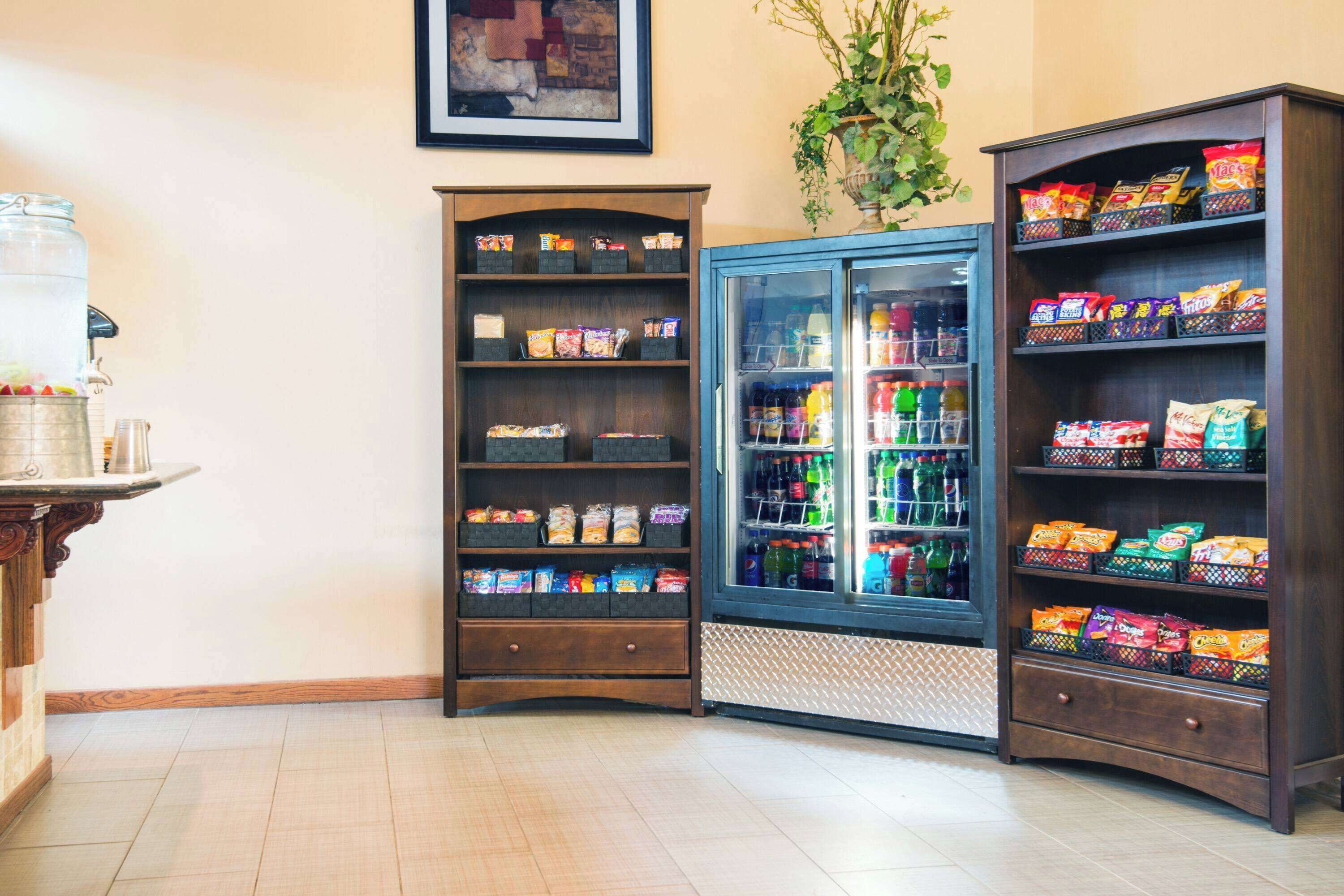A corner with a refrigerated display case and shelves stocked with snacks and beverages.
