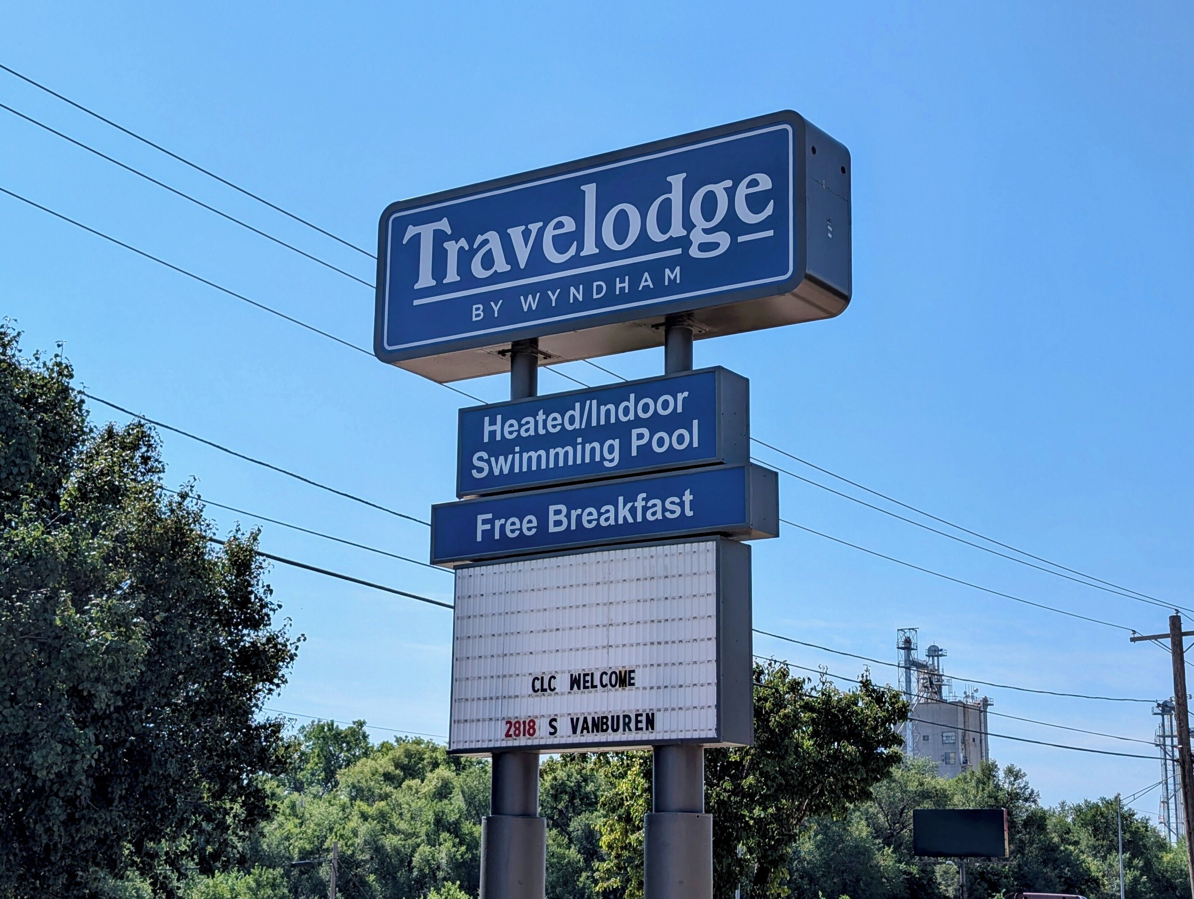 Une enseigne indiquant la présence d’un hôtel Travelodge by Wyndham, mettant en avant ses équipements, notamment une piscine intérieure chauffée et un petit-déjeuner gratuit.