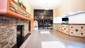 Un hall con chimenea de piedra, mostrador de recepción y un amplio ventanal.