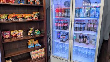 Geladeira com lanches e bebidas, incluindo salgadinhos e refrigerantes.