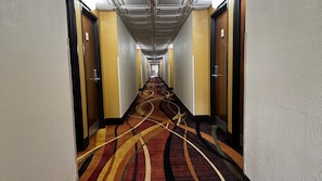 Corridors lead to spacious rooms with carpeted floors and grid-patterned ceilings.