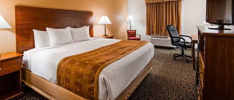 Habitación de hotel con una cama grande, dos mesitas de noche, un escritorio con silla, televisión y aire acondicionado.