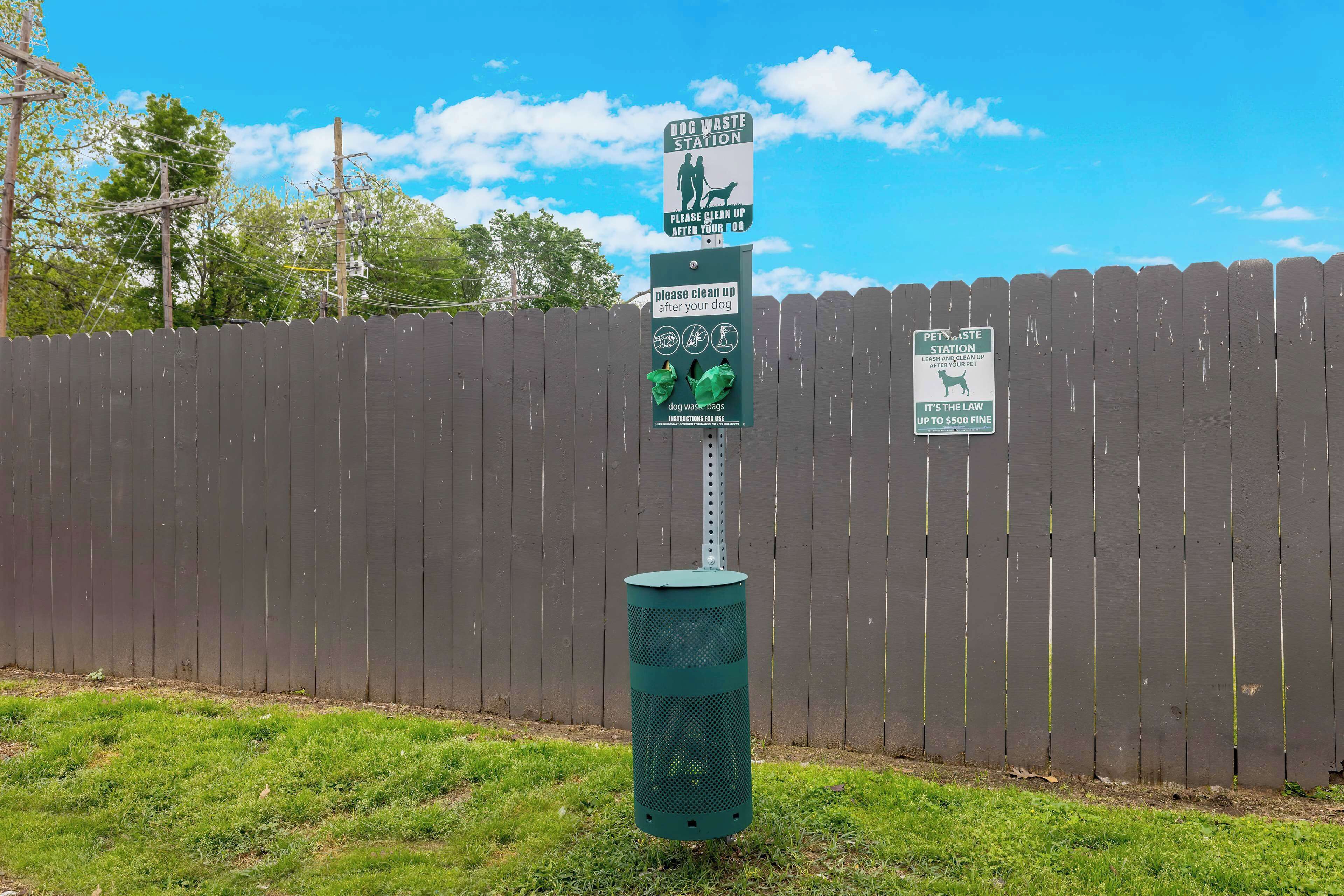 A dog waste station with a sign instructing to clean up after your dog.