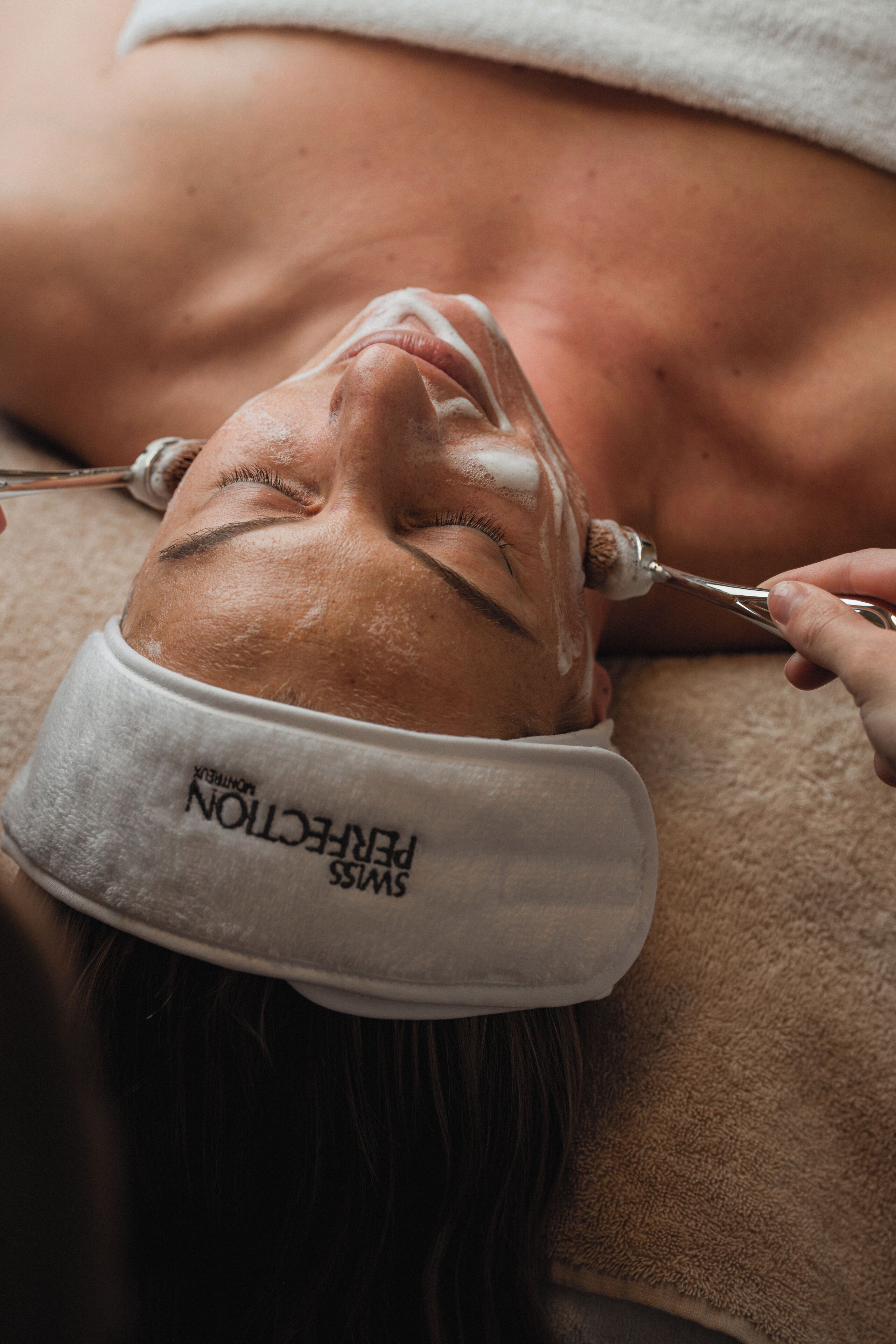 A person receiving a facial treatment with a towel and a headband.