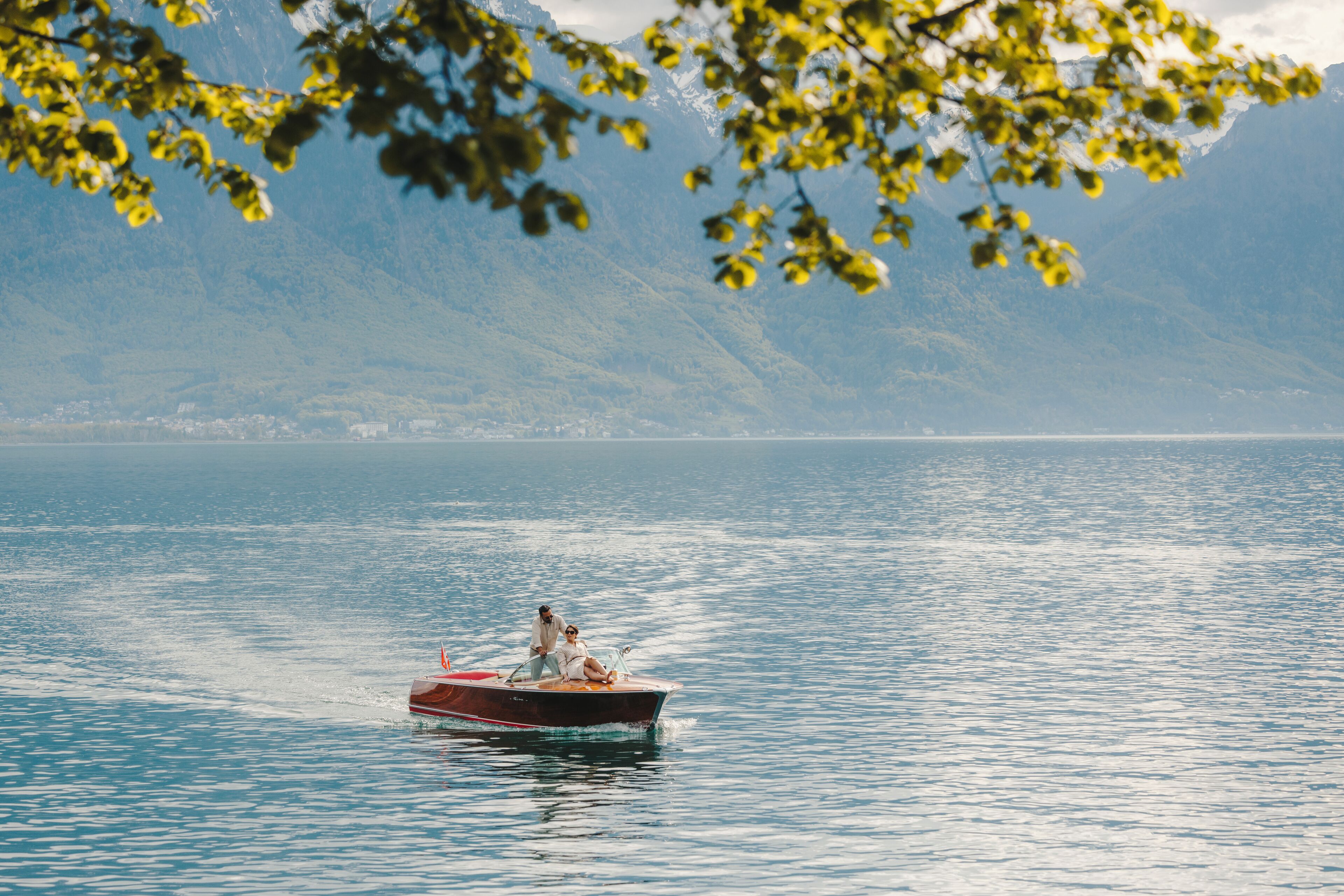 A boat on a calm lake with mountains in the background.