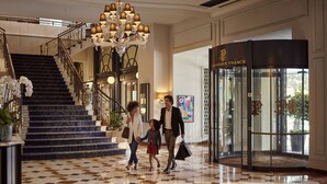 A grand lobby with a marble staircase, a chandelier, and a revolving door labeled "Montreux Palace".