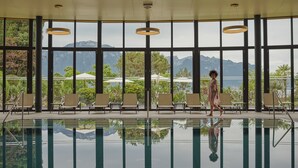 Un área de piscina con sillas y vistas a montañas a través de grandes ventanales.