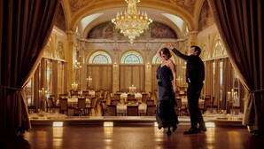 Un salón de baile imponente con candelabros ornamentados, ventanas en arco y un suelo reflectante.