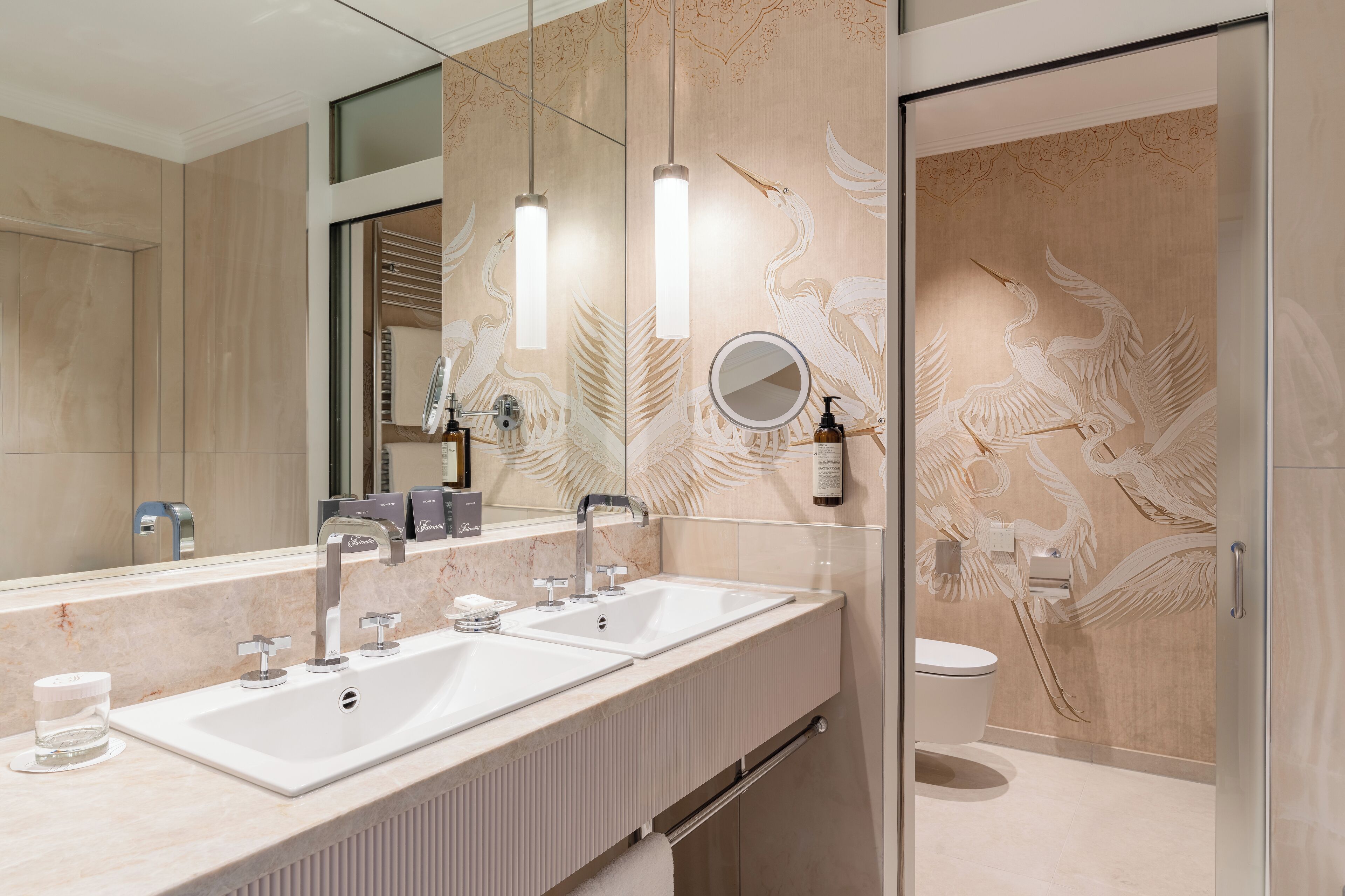 A modern bathroom with a double sink vanity, a large mirror, and a toilet.