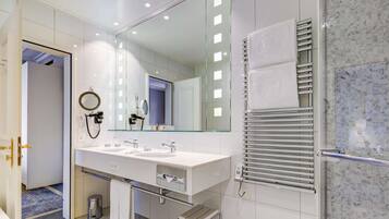Une salle de bain moderne dotée d’un grand miroir, de deux vasques, d’un porte-serviettes et d’une cabine de douche en verre.