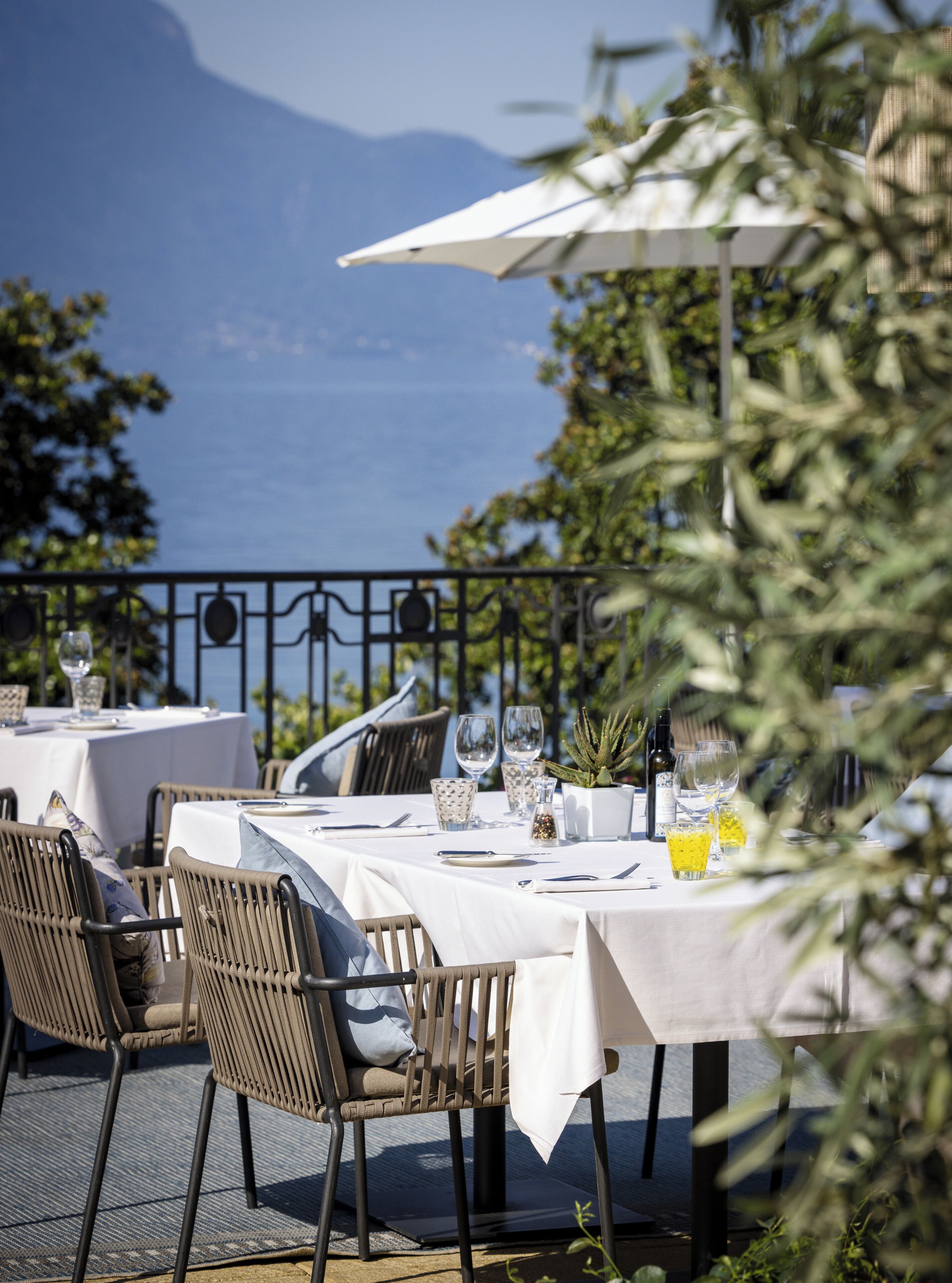 Un espace de restauration en plein air avec des tables pour deux personnes, des chaises et une vue sur la mer.