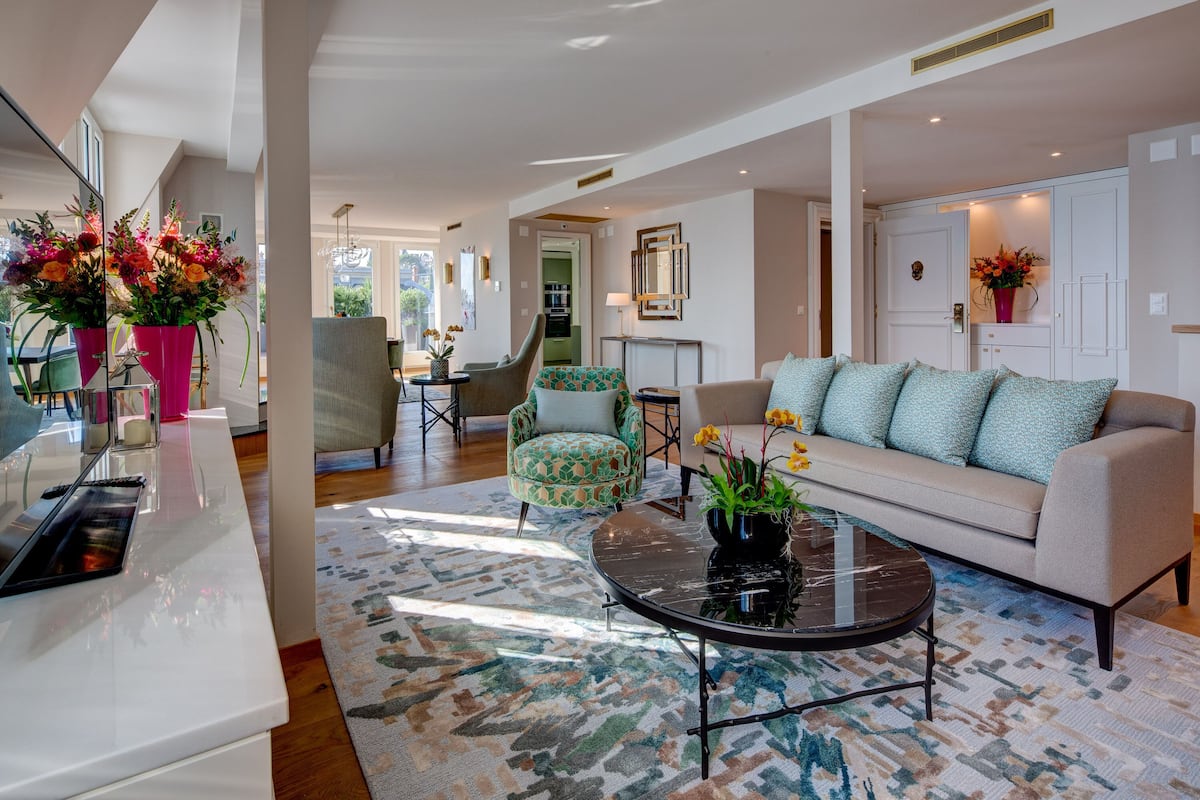 A modern living room with a sofa, armchairs, a coffee table, and a dining area with chairs and a table.