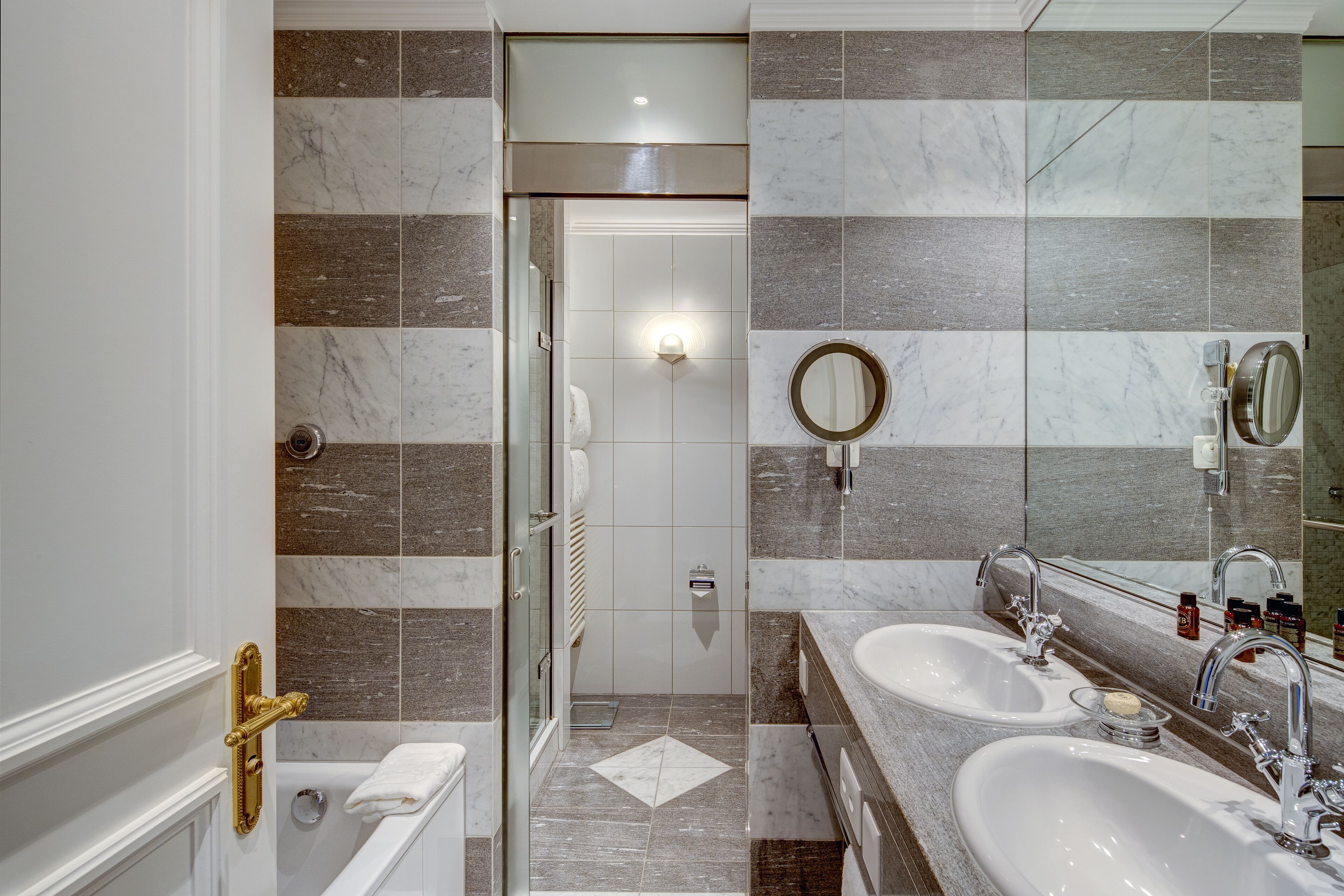 Ein modernes Badezimmer mit zwei Waschbecken, einem großen Spiegel und einer Duschkabine.