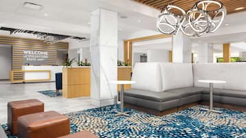 Un área de recepción moderna con un mostrador de mármol, un sofá modular gris y una alfombra estampada azul.