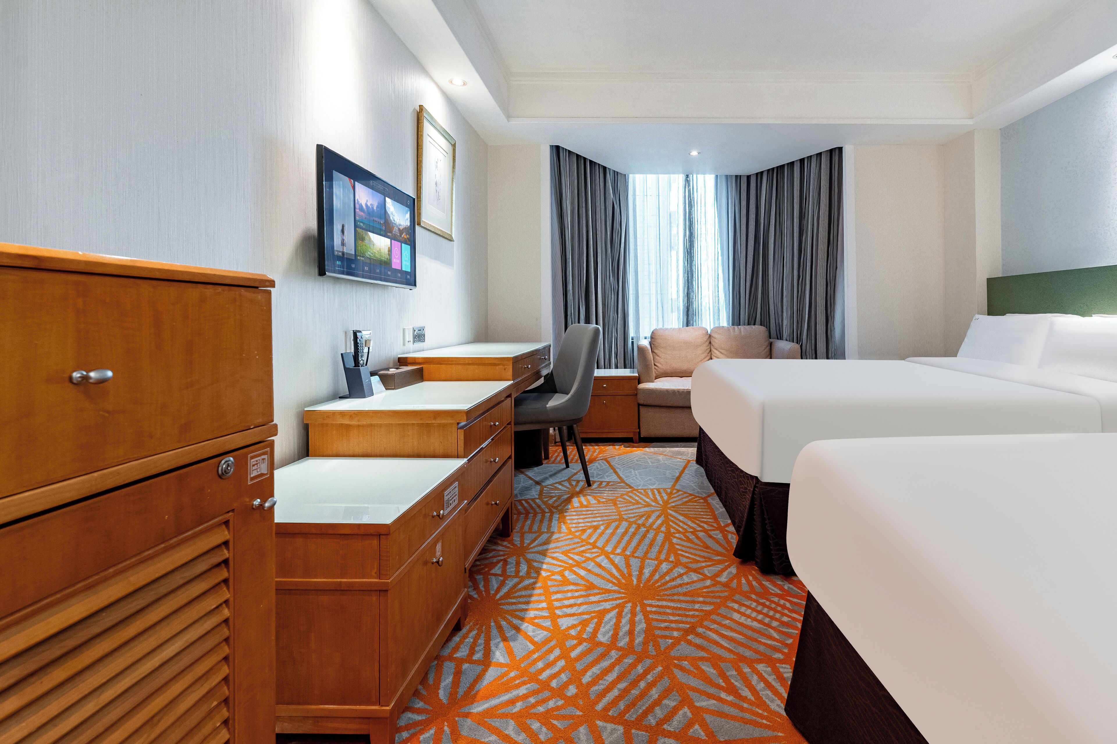 Habitación de hotel con cama, escritorio, silla, armario y una ventana grande con cortinas.