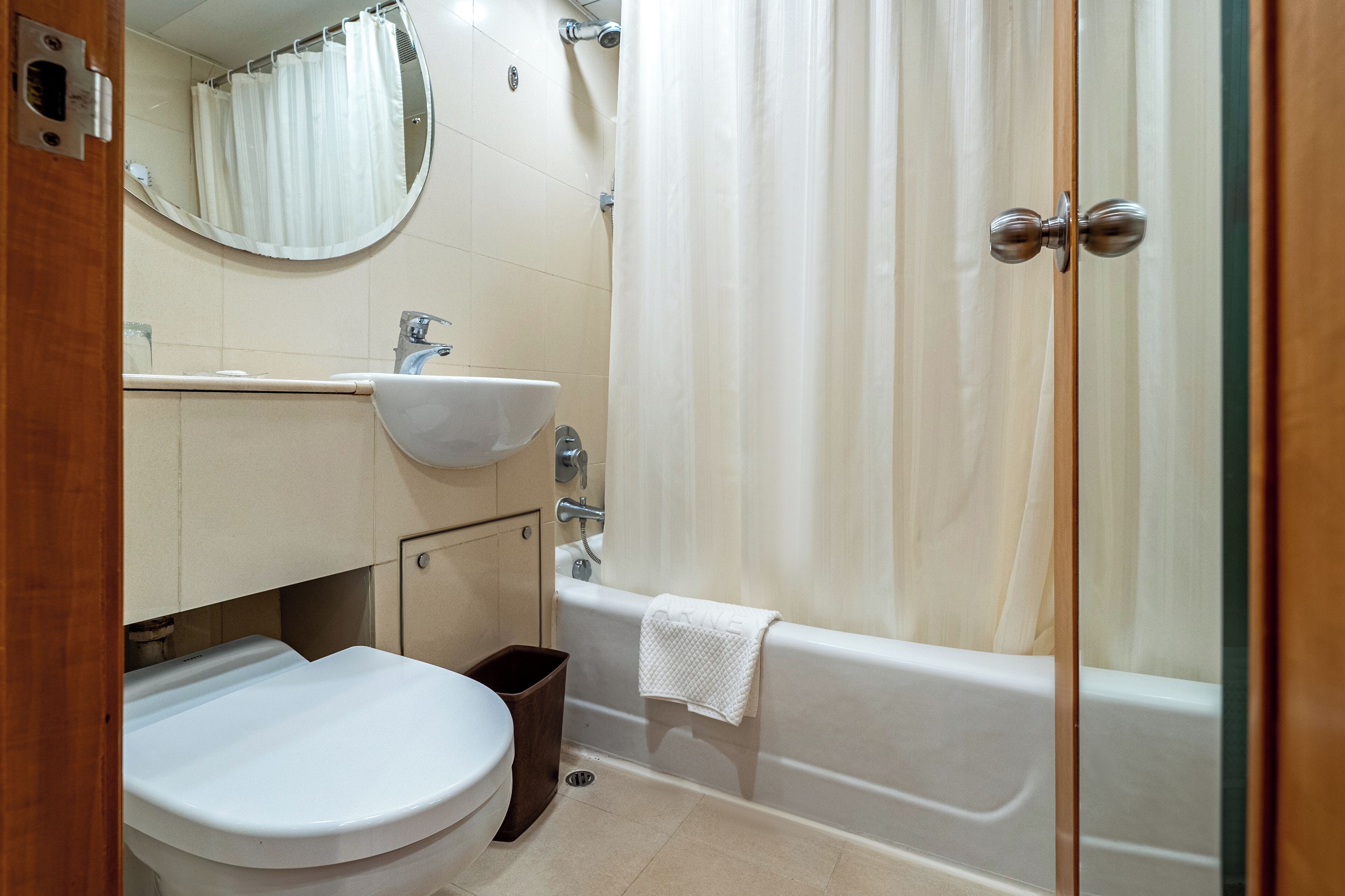 A bathroom with a toilet, sink, bathtub, and a mirror.