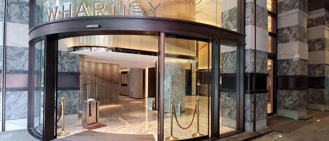 A hotel entrance with a curved facade, marble flooring, and a red rope barrier.