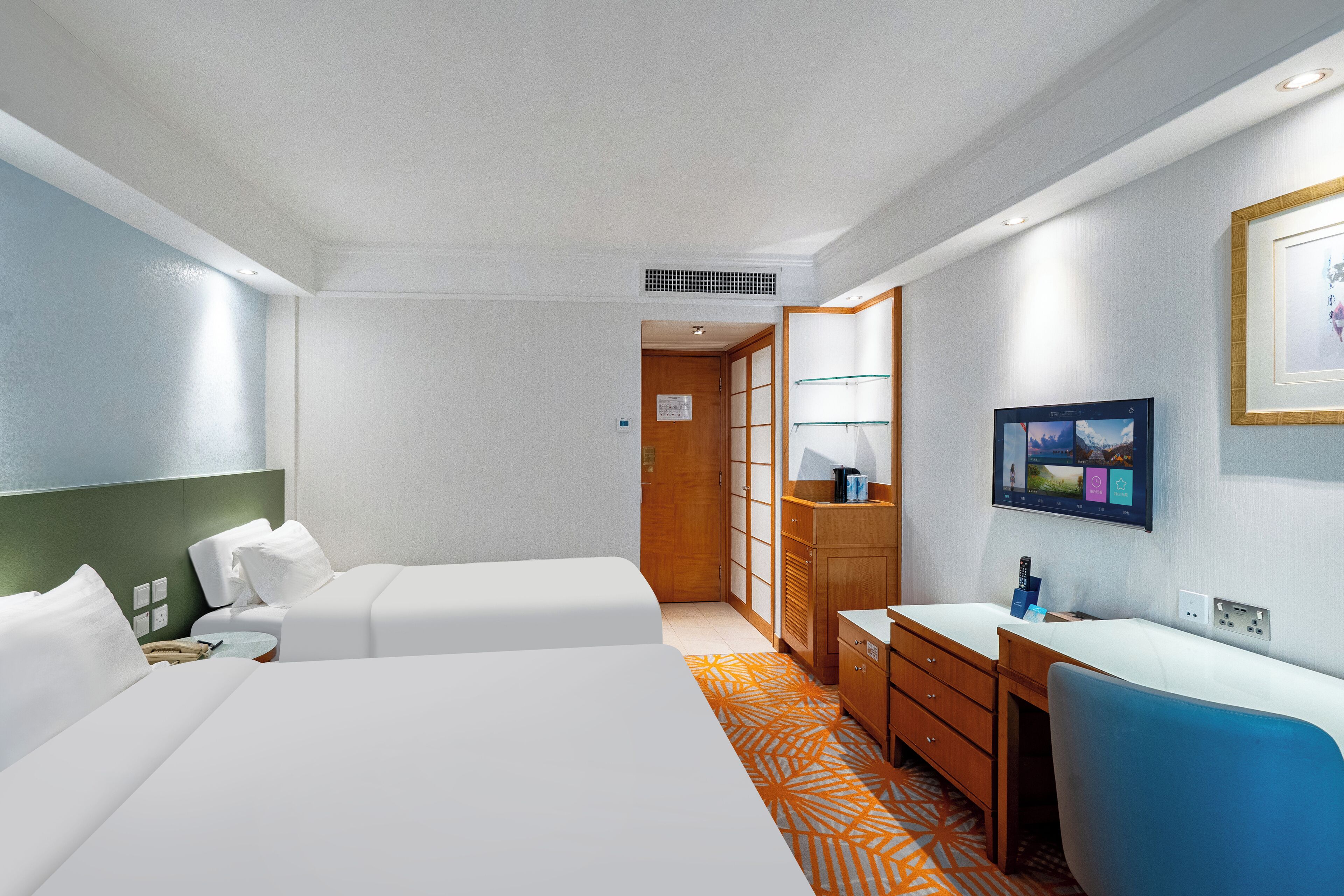 A hotel room with two beds, a desk, a chair, a TV, and a wardrobe.