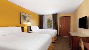 Habitación de hotel con dos camas, un escritorio, un televisor y una ventana con cortinas.