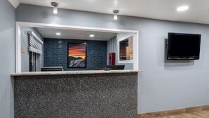 Un área de recepción con mostrador de baldosas, un cuadro enmarcado y un televisor instalado.