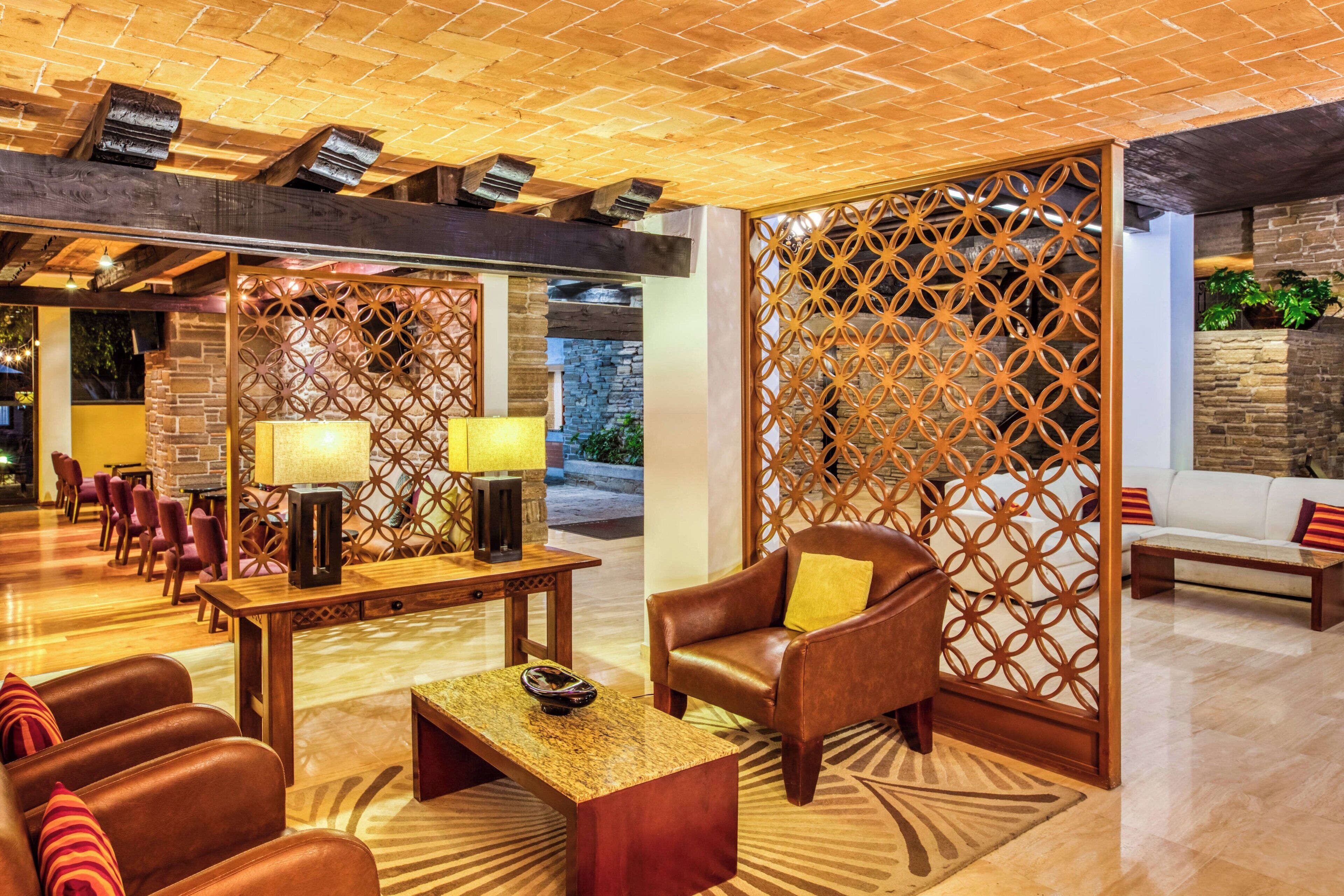 A lobby with leather sofas, a wooden coffee table, and a patterned floor.