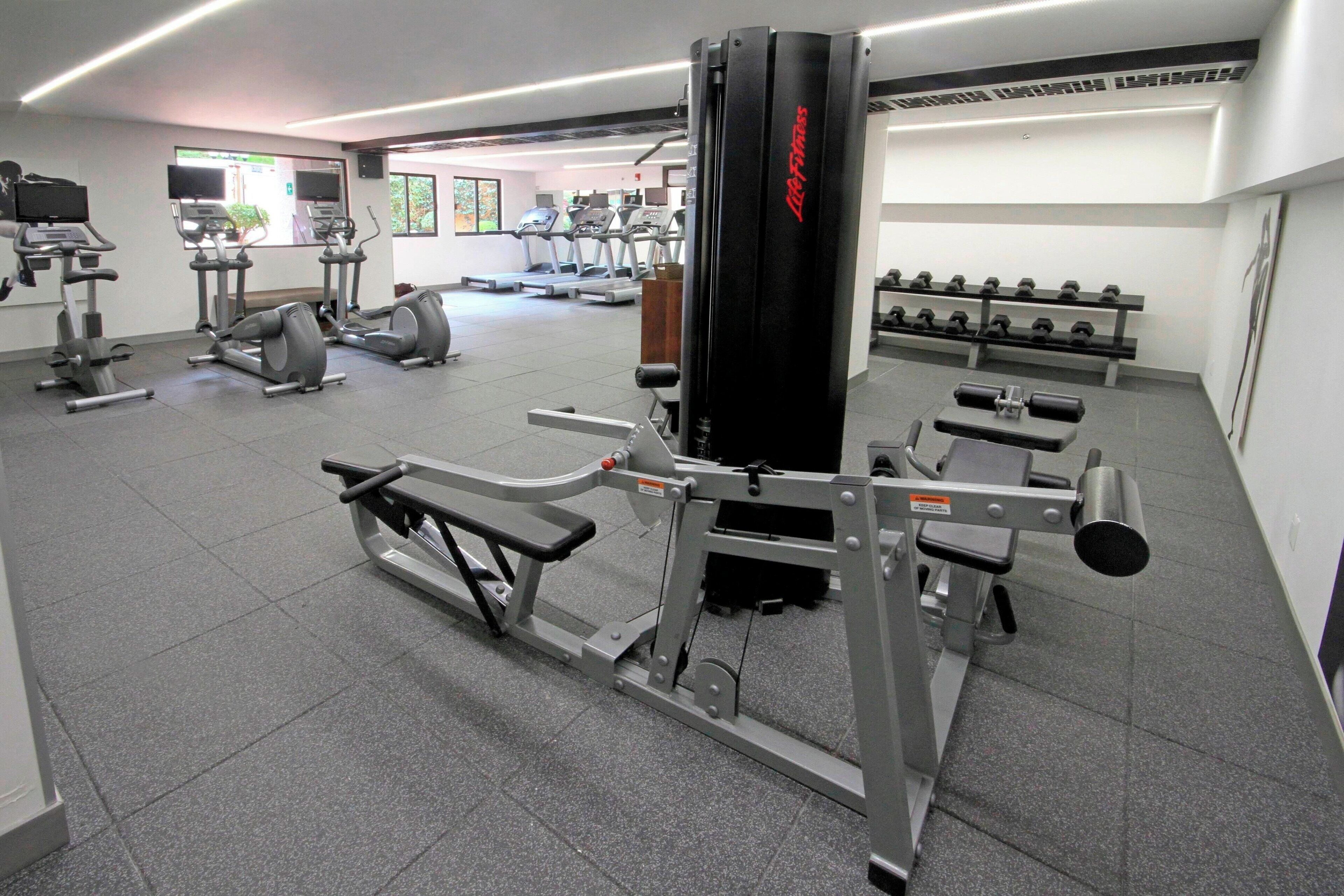 Une salle de sport équipée de tapis de course, de vélos elliptiques et de matériel de musculation.