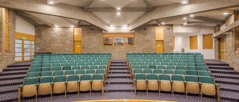 A conference room with tiered seating, stone walls, and wooden floors.