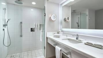 A modern bathroom with a glass-enclosed shower, a large mirror, and a white sink with two towel racks.