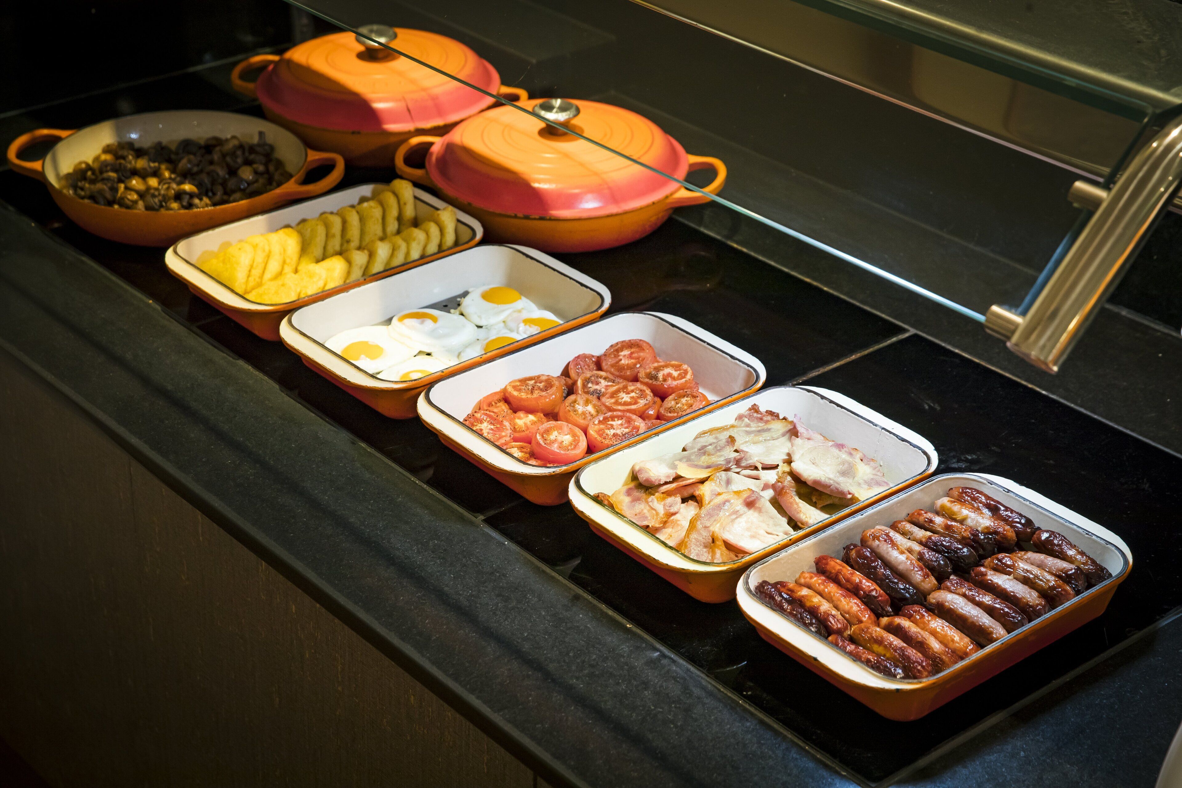 A buffet with various food items including eggs, tomatoes, sausages, and other dishes.