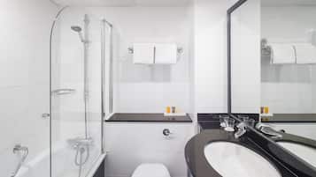 A modern bathroom with a glass-enclosed shower, a white toilet, a black sink, and a large mirror.