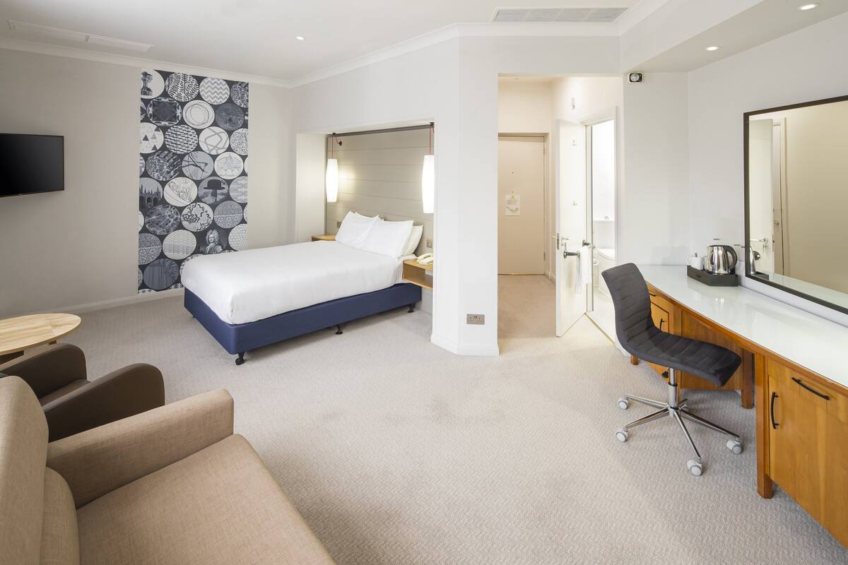 Une chambre d’hôtel équipée d’un lit, d’un bureau, d’une chaise et d’un téléviseur.